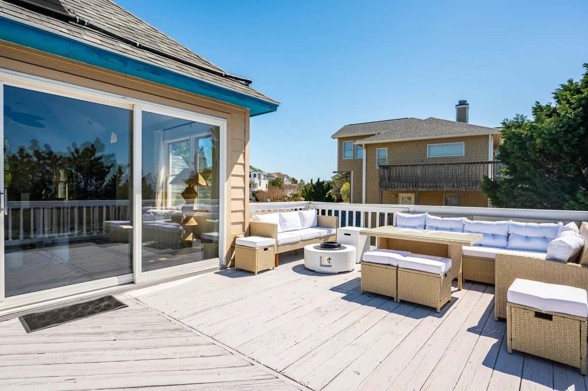 This photo captures a welcoming outdoor seating area centered around a fire pit, with a glass sliding door that visually connects the space to the home's interior. The fire pit is ready for evening gatherings, stargazing, or sharing stories after a day of fun.