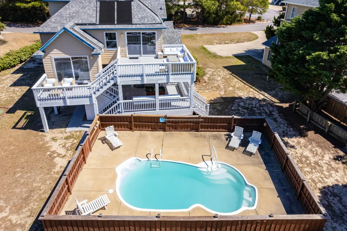 This image showcases a sparkling swimming pool surrounded by a deck area with lounge chairs, all set against the backdrop of the house exterior. The space radiates an inviting, resort-like atmosphere, perfect for swimming, sunbathing, or relaxing with friends and family.