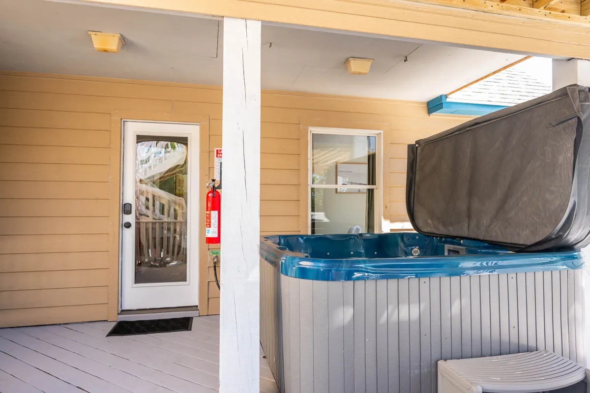 A cozy outdoor hot tub sits adjacent to the home's entrance, offering sunset views. The setup is ideal for unwinding after a day at the beach or during cooler evenings, reinforcing the property's year-round relaxation appeal.